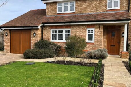 Large house with brick walls with natural wood tone garage doors