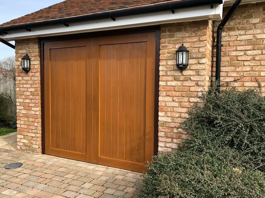 A wood-tone automated up-and-over GRP garage door with elegant paneling and a natural finish.