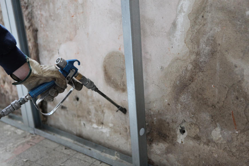 Man spraying insulation into walls